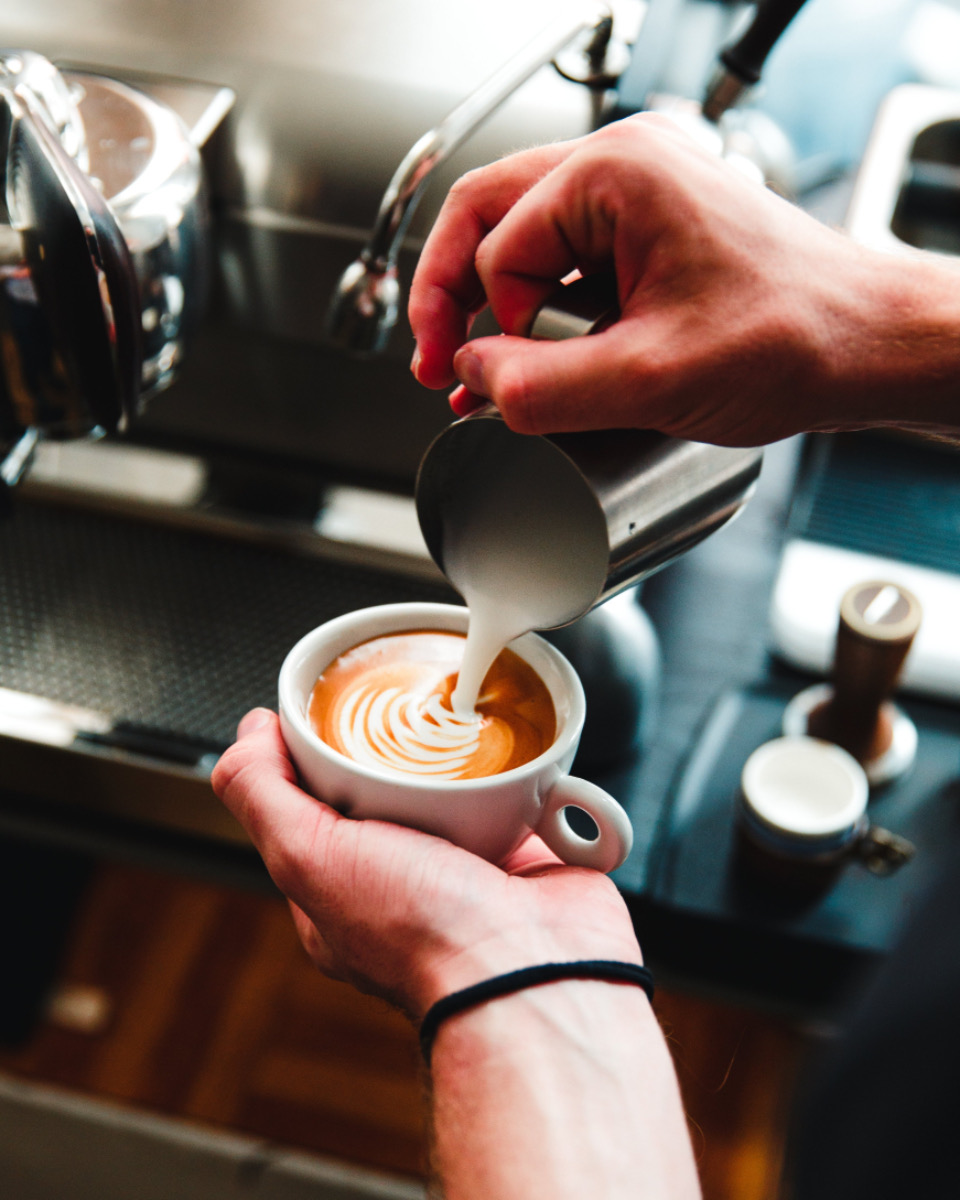 Barista hælder mælk i en cappuccino